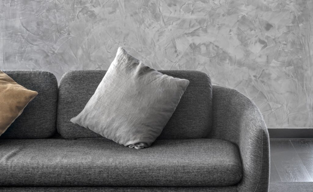 grey polished plaster behind a grey couch with cushions